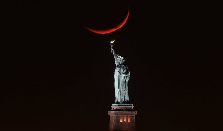 A crescent moon sets behind the Statue of Liberty on Jan. 19, 2018 in New York City.