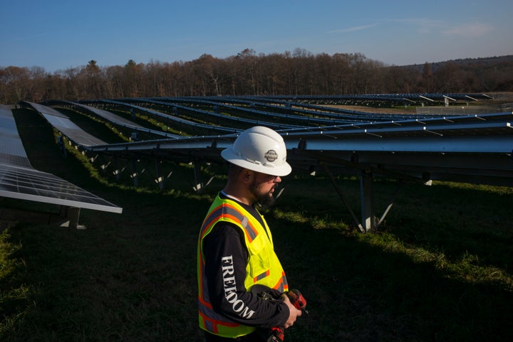 Employees from a Radian Generation's operations and maintenance team change out a faulty solar inverter along a row of solar panels on Dec. 4, 2017, at the family-owned Knowlton Farm in Grafton, Massachusetts.