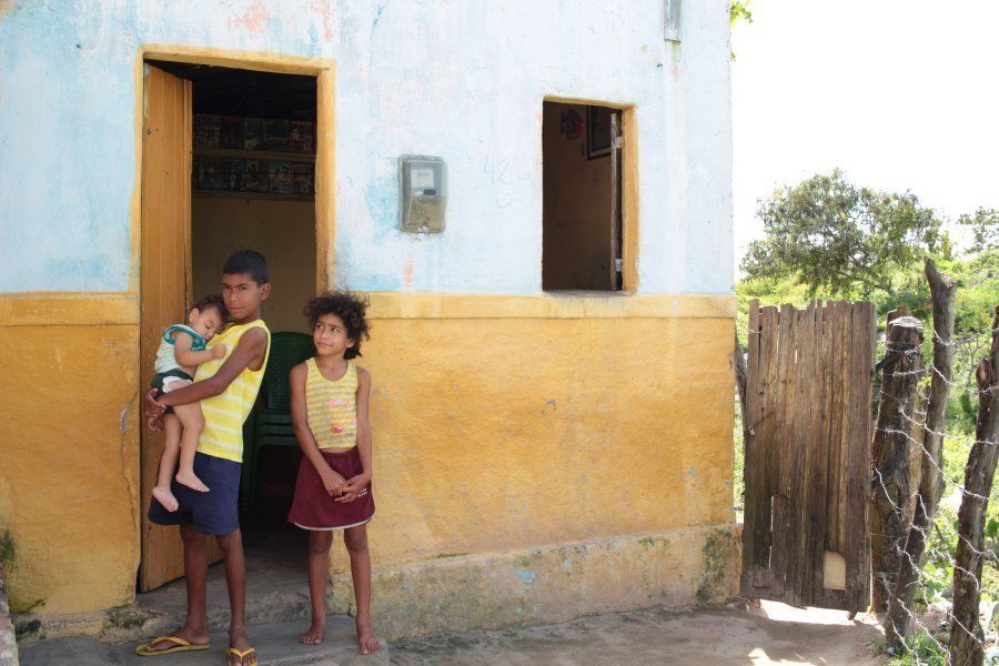 Three of Silva’s children — Gabriel, 2; Paulo, 11; Paulina, 9 — stand outside the family’s home.