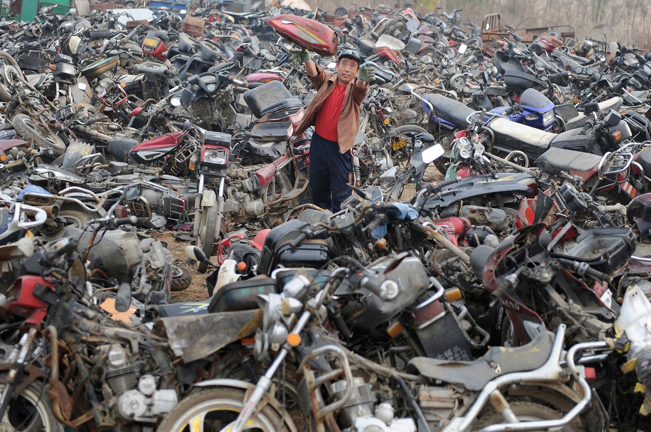 A laborer disassembles motorcycles at a recycling factory in Hefei, Anhui province, China in 2009.
