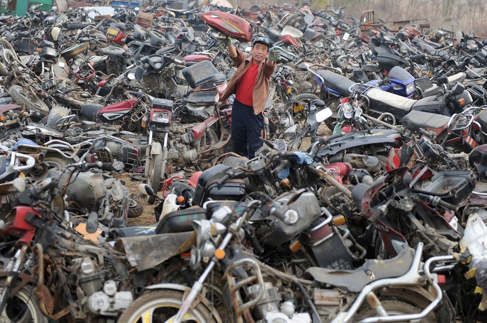 A laborer disassembles motorcycles at a recycling factory in Hefei, Anhui province, China in 2009.