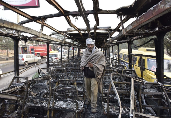 A bus conductor stands inside a bus that was set on fire near the village of Bhondsi in Gurgaon, allegedly by activists of Karni Sena, who were protesting against the release of film "Padmaavat." 