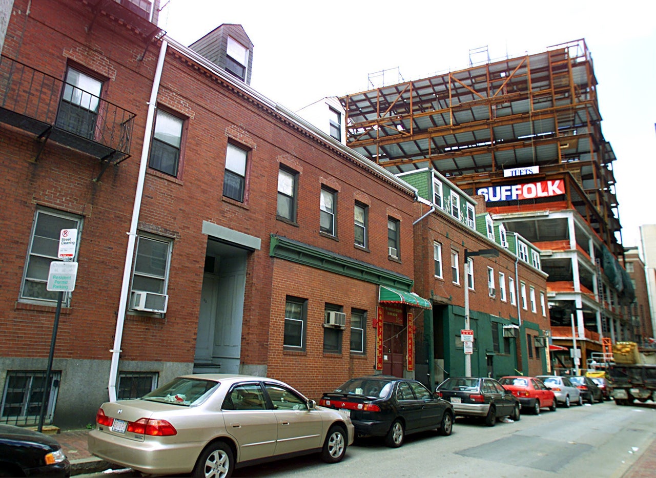 Construction by Tufts University on Tyler Street in Chinatown near traditional row homes, which residents worry will either be demolished or turned into expensive condos.