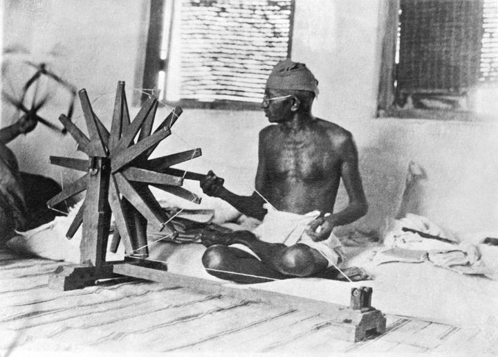 Gandhi making homespun cotton to boycott English merchandise and boost Indian economic self-sufficiency 