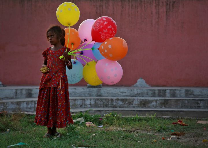 A young girl sells balloons by the Yamuna River on the last day of the Ganesh Chaturthi festival in Delhi, India, on Sept. 15, 2016.