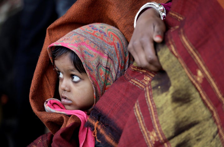 A little girl wrapped in a shawl waits along with her mother at a railway station in New Delhi, India, on the cold winter morning of Jan. 3, 2018.