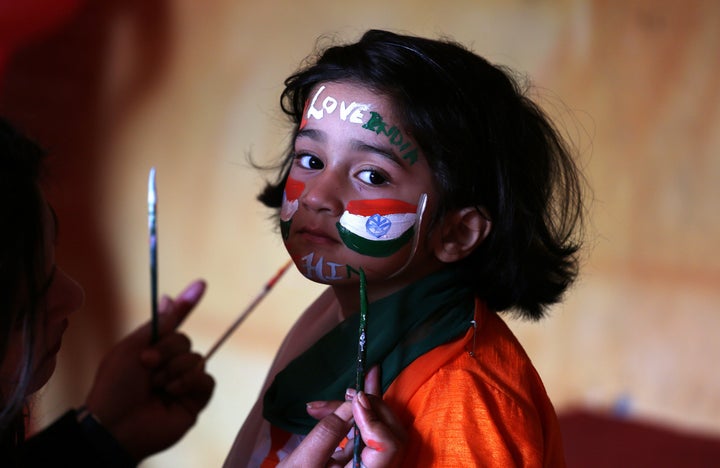 A school girl gets her face painted in the colors of India's national flag before taking part in the country's Republic Day c