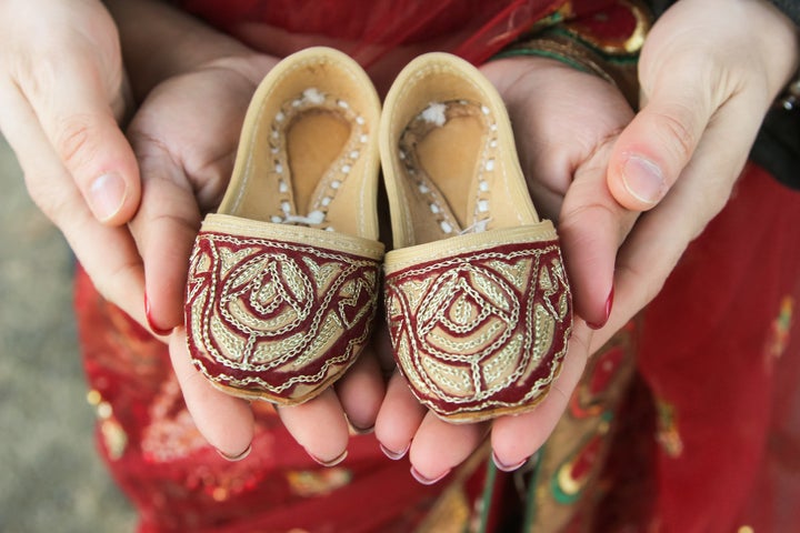 Sherine and Alessandro Valverde hold juttis, traditional Indian dress shoes, during their maternity shoot.