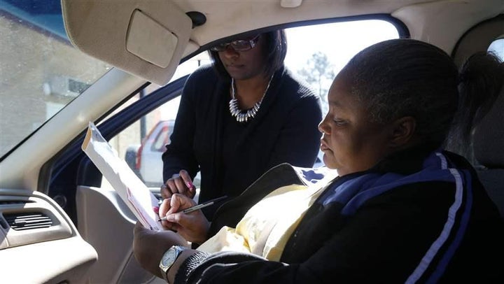 A South Carolina voter, prevented from entering a polling place by her physical disability, receives assistance from a poll worker on the day of the state’s 2016 Democratic presidential primary. More people with disabilities are encountering barriers to voting, a problem that is being exacerbated by the widespread return to paper ballots.