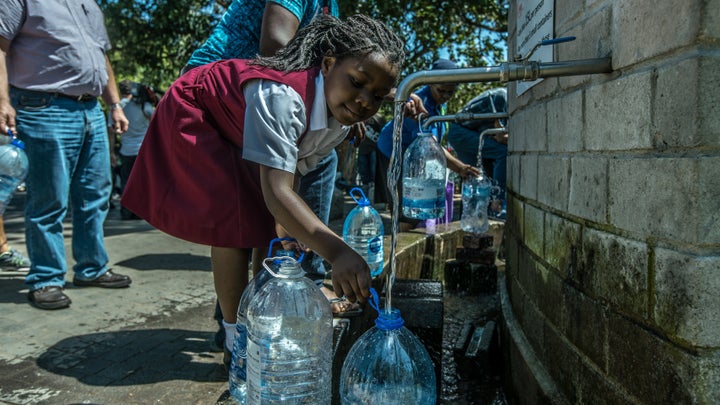 A little girl helps fill water bottles at Newlands Brewery Spring Water Point in Cape Town on Tuesday.