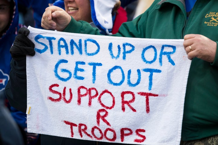 Football fans wave a hand-painted sign demanding players stand for the national anthem during a game between the Buffalo