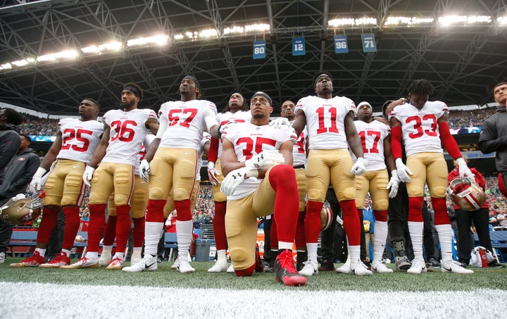Eric Reid of the San Francisco 49ers kneels during the national anthem with his teammates' support, prior to a