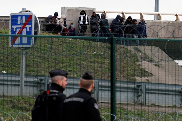 Four migrants are in a critical condition after being shot in Calais, and two others also suffered gunshot wounds in a mass-brawl; migrants are seen gathering near a bridge as French gendarmes patrol the area