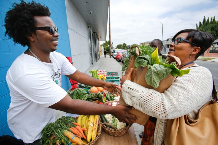 Dyane Pascall, Director of Finance for Community Services Unlimited, hands over a large bag of produce to customer Karyn Williams, at produce stand set up outside St. John's Well Child and Family Center's S. Mark Taper Foundation Health Center in South Los Angeles on June 3, 2013.