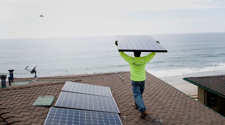 Andres Quiroz, an installer for Stellar Solar, carries a solar panel during installation at a home in Encinitas, California.