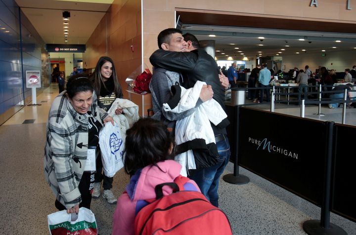 Rami Al-Qassab, at right, hugs his brother after being reunited with his Iraqi refugee mother Amira, left, and siblings after they arrived at Detroit Metro Airport in Romulus, Michigan, Feb. 10, 2017.