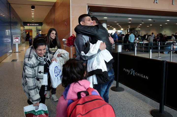 Rami Al-Qassab, at right, hugs his brother after being reunited with his Iraqi refugee mother Amira, left, and siblings after they arrived at Detroit Metro Airport in Romulus, Michigan, Feb. 10, 2017.