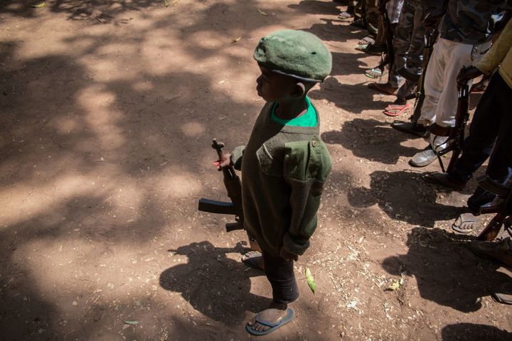 A newly-released child soldier stands with his rifle during a ceremony on Feb. 7, 2018.