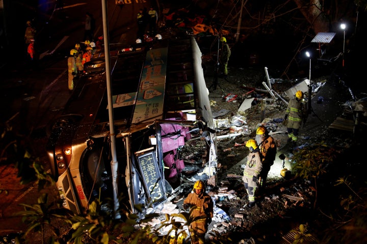 Rescuers walk beside the crashed bus.
