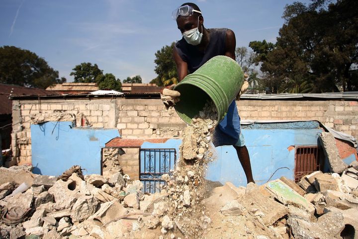 Haitians clean up the debris in a house that was destroyed in the last earthquake of 2010.