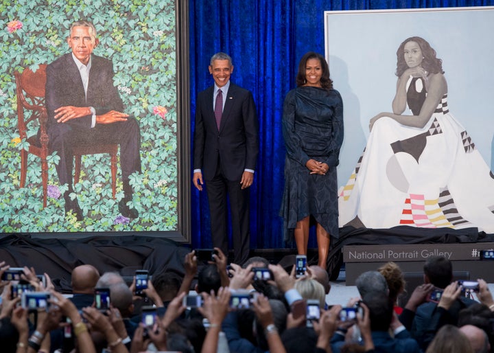 Barack and Michelle Obama with their portraits.