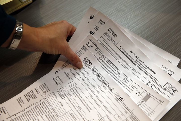 FILE – In this Jan. 14, 2017 file photo, tax professional and tax preparation firm owner Alicia Utley reaches for hard copies of tax forms while working to stay caught up at the start of the tax season rush in her offices at Infinite Tax Solutions, in Boulder, Colo. Millions of working Americans should start seeing fatter paychecks as early as next month, the IRS says, as a result of the recently passed tax law. 