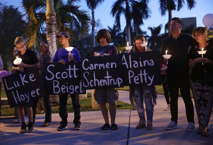 Mourners hold signs with the names of some of the 17 people killed during a shooting at Marjory Stoneman Douglas High School at a candlelight vigil on Friday in Boca Raton, Florida.