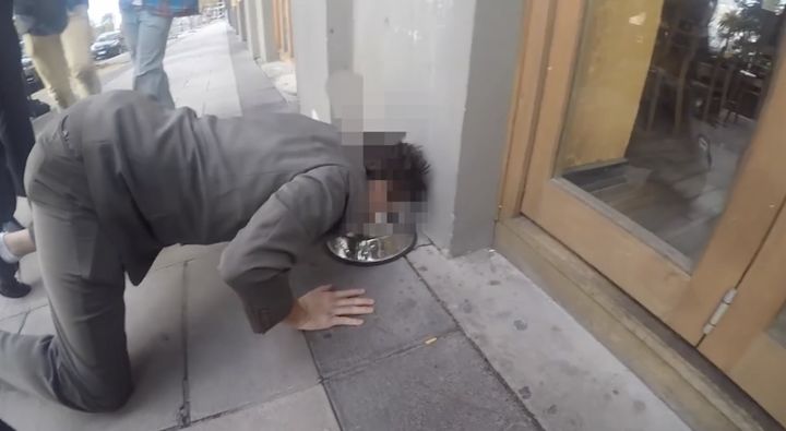 A "fresher" at the University of Newcastle in Australia drinks from a public dog bowl on a sidewalk.