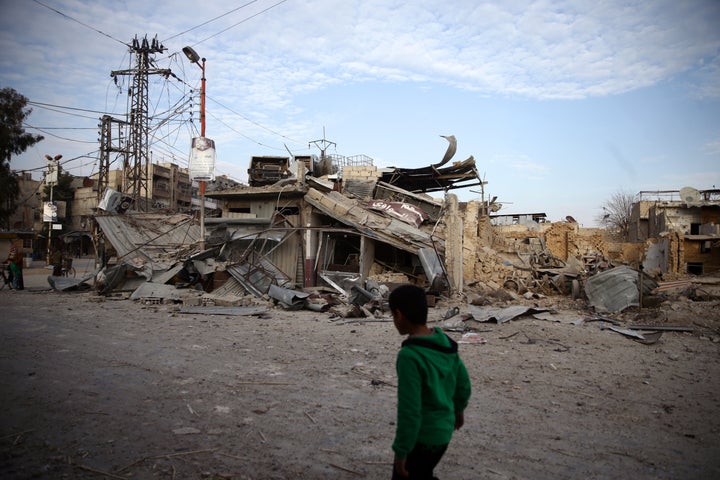 A child walks near damaged buildings in the besieged town of Douma, Syria, on Feb. 20, 2018.