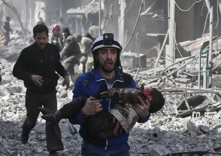 A Syrian civil defense member carries an injured child after a government bombing in the rebel-held town of Hamouria in Syria's besieged eastern Ghouta region.