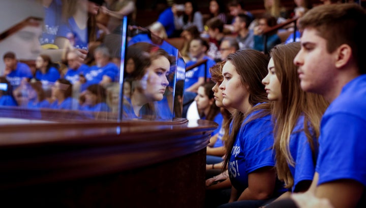 Students from Marjory Stoneman Douglas High School, wearing blue T-shirts, look on from the gallery above the Florida Senate.