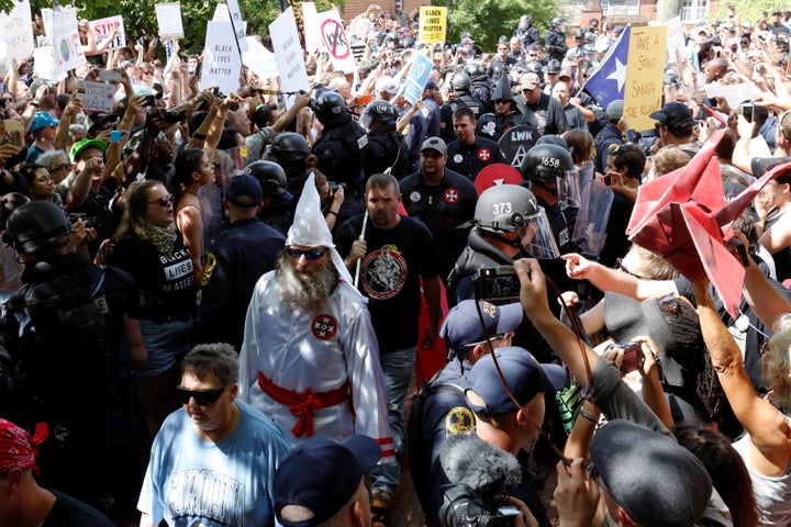 Riot police protect members of the Ku Klux Klan from counter-protesters as they arrive to rally in opposition to city proposa