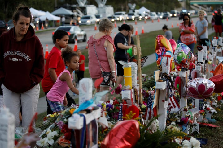 People grieve in front of crosses and Stars of David placed in front of the fence of the Marjory Stoneman Douglas High School to commemorate the victims of the mass shooting, in Parkland, Florida, U.S., Feb. 21, 2018