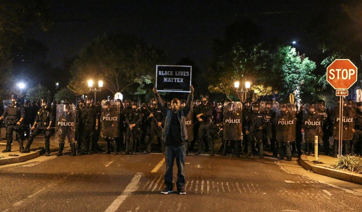 A Black Lives Matter protester stands in front of St. Louis Police Department officers equipped with riot gear on Sept. 15, 2017.