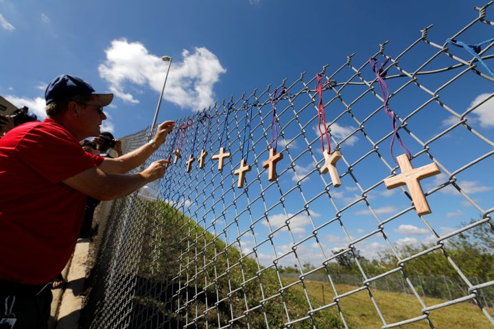 Bob Ossler, chaplain with the Cape Coral volunteer fire department, affixes 17 crosses on a fence for the victims of the Marjory Stoneman Douglas High School shooting.