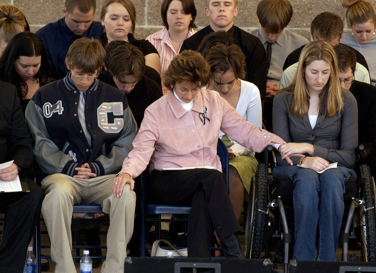 Anne Marie Hochhalter (right) prays during an event to remember those lost during the Columbine attack. She says she became disillusioned with her lawmakers over time.