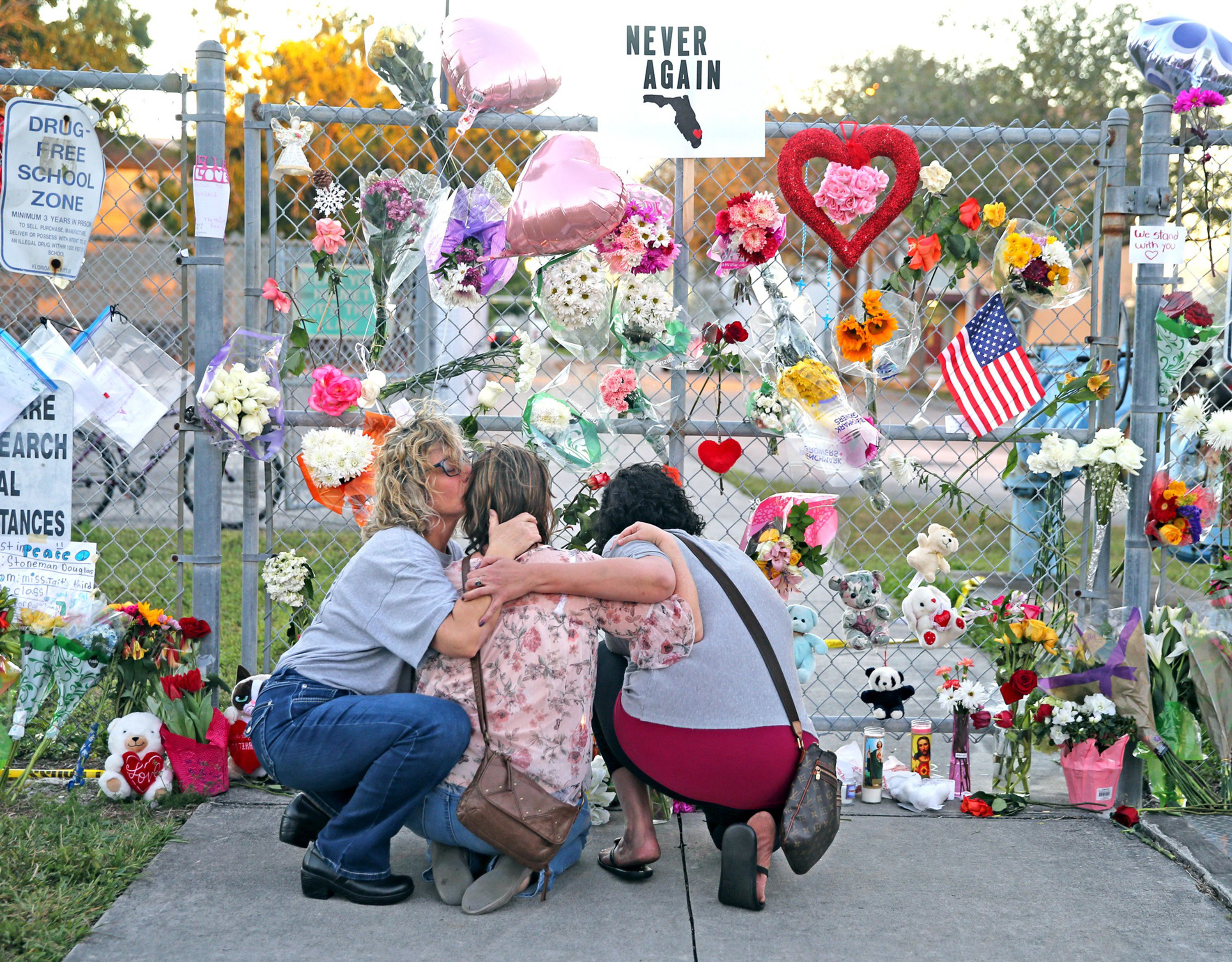 <strong>Shari Unger kisses Melissa Goldsmith as Giulianna Cerbono lights candles at a memorial at Marjory Stoneman Douglas High School where a gunman killed 17 students on February 14</strong>