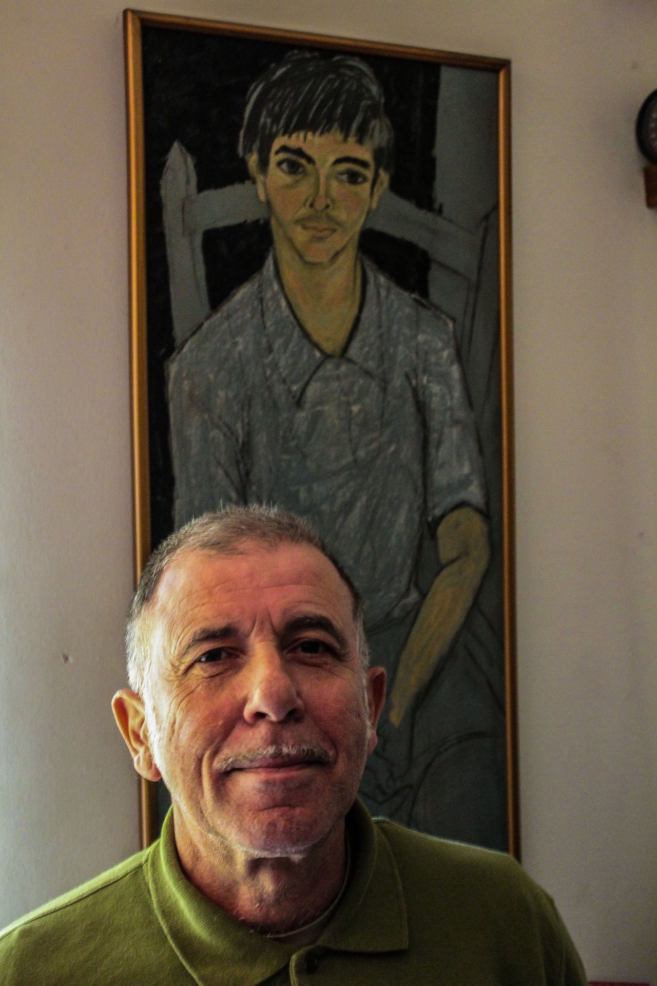 Ο Νικόλας Χρηστάκης με φόντο τον ίδιο στα 15 του, όπως τον ζωγράφισε ο πατέρας του. 