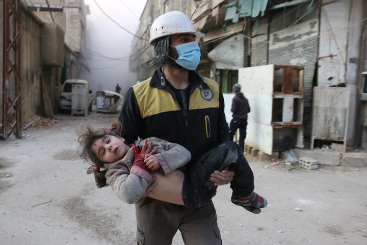 Civil defense team member carries a wounded baby rescued from a wreckage after Assad regime forces carried out airstrikes ove