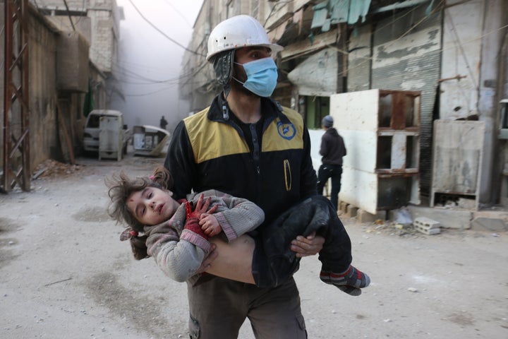 Civil defense team member carries a wounded baby rescued from a wreckage after Assad regime forces carried out airstrikes over the de-escalation zone in Arbin town of Eastern Ghouta in Damascus, Syria on February 23, 2018.