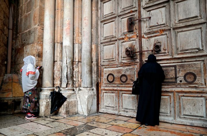 Two Christian women pray by the closed door of the main entrance of the Church of the Holy Sepulchre in the Old City of Jerusalem on February 26, 2018, after Christian leaders took the rare step of closing the church.