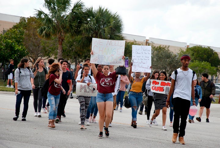 Students from Coral Glades High School hold signs as they participate in a school walk for gun law change on Feb. 21.