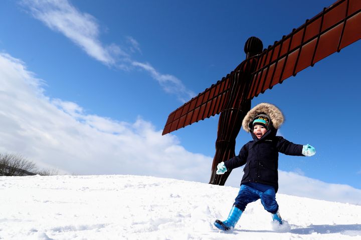 A boy plays in the snow next to the Angel of the North near Gateshead
