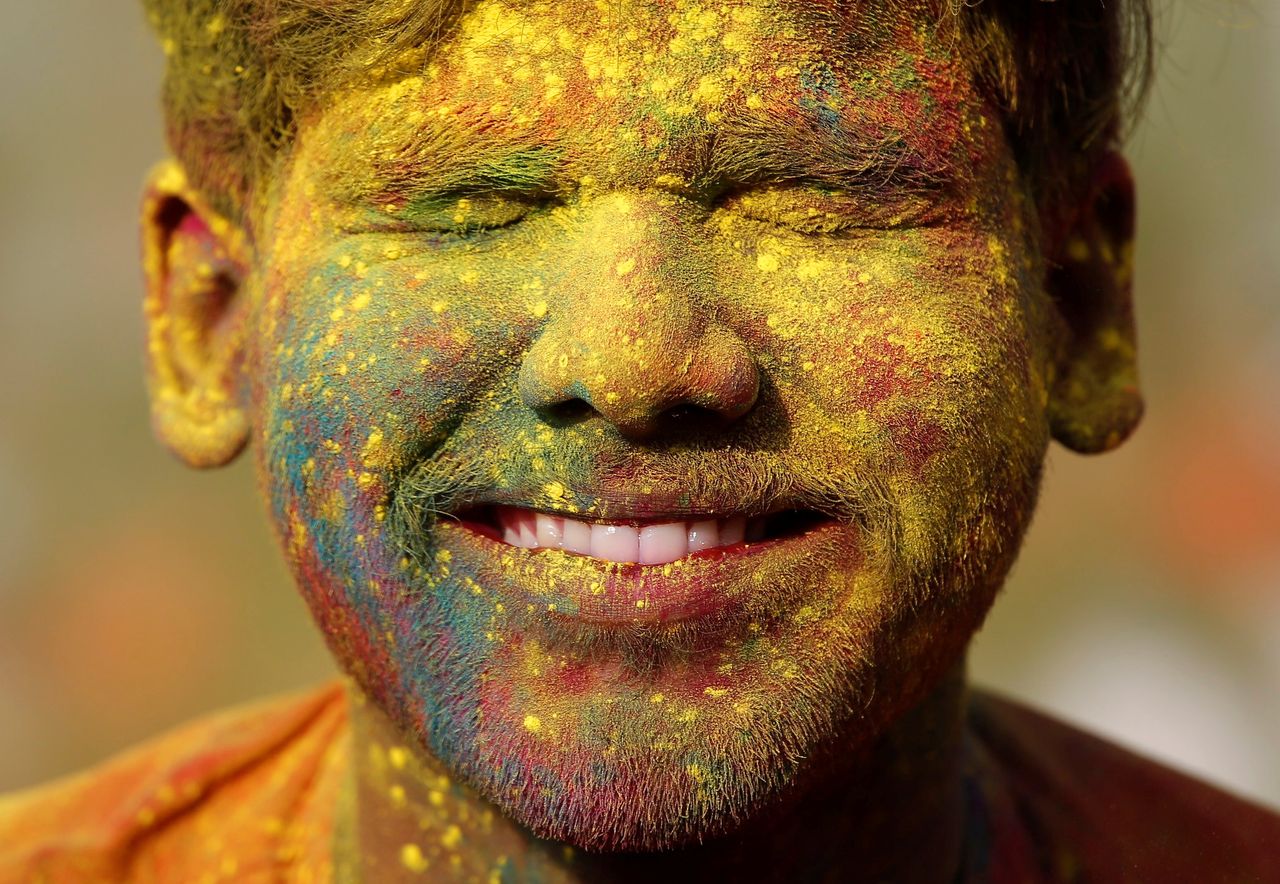 A student of Rabindra Bharati University, with his face smeared in colored powder, reacts in Kolkata, India.