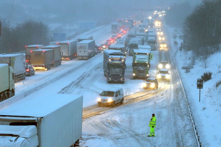 Drivers manoeuvre their cars past stationary lorries on the M80 Haggs in Glasgow, as the highest level of weather warning has been issued for Scotland and Ireland as forecasters warn of 'blizzard-like' conditions.