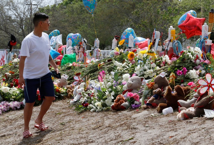 A young man views memorials on a fence surrounding Marjory Stoneman Douglas High School in Parkland, Florida, U.S., February