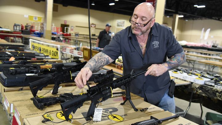 Two days after the massacre at Marjory Stoneman Douglas High School in Parkland, Florida, a vendor sets up his display of AR-15 assault-style rifles for the South Florida Gun Show in Miami.