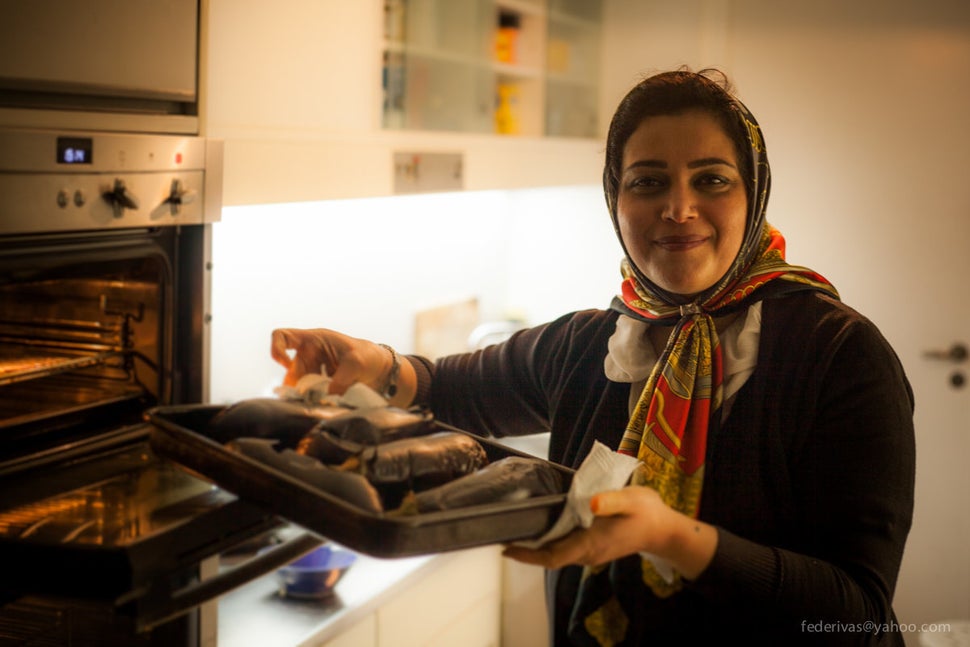 Elahe pulls some aubergines out of the oven.