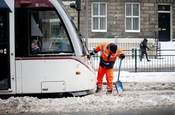 An engineer clears snow and ice from the tram lines along York Place in Edinburgh as severe weather conditions continue