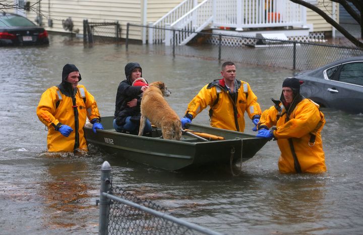A mother and child and a dog are rescued from a flooded home on Post Island Road in the Houghs Neck section of Quincy, MA.
